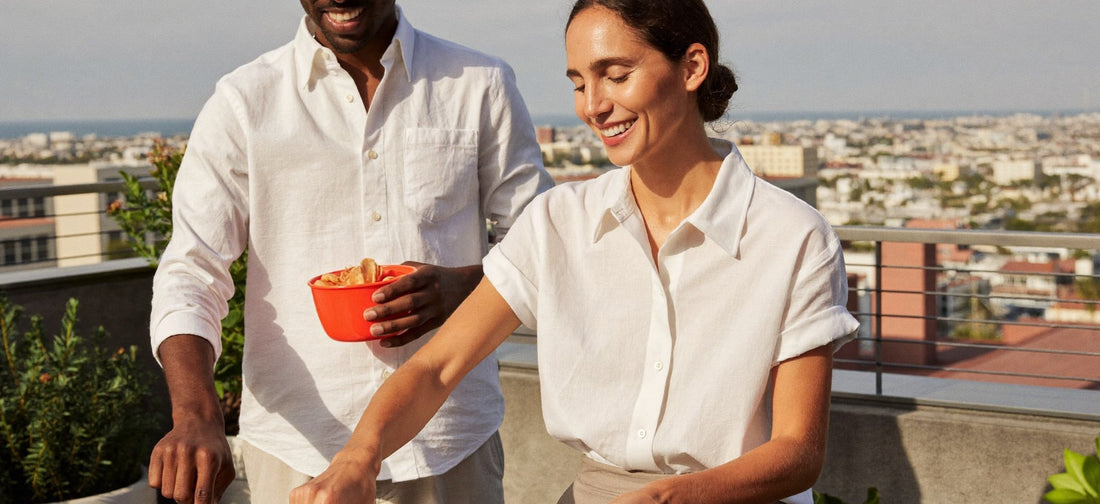 Two young adults chatting while preparing brunch on a sunny rooftop