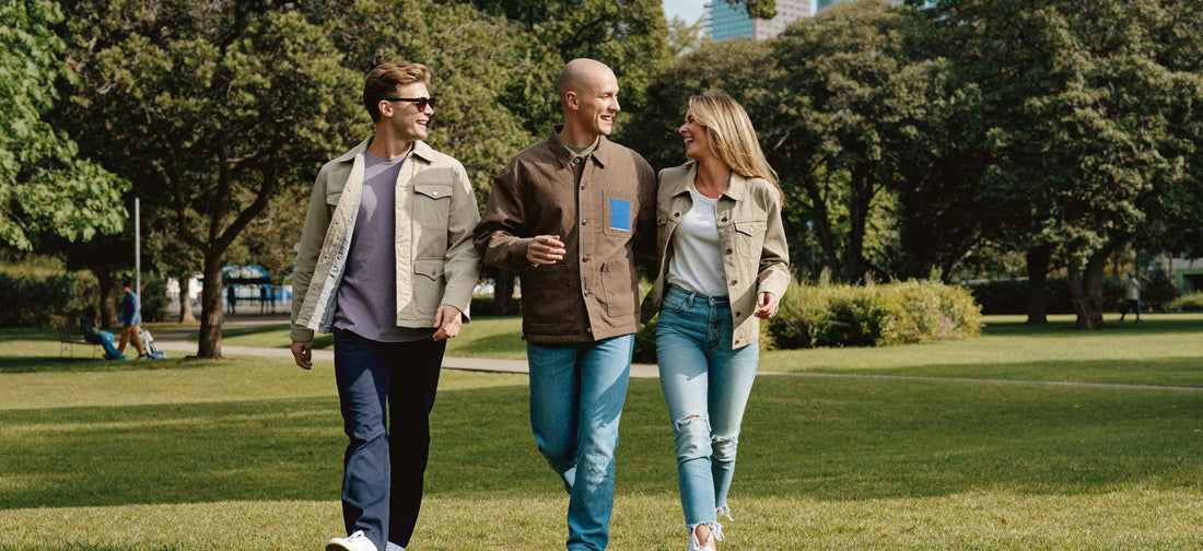 Three young adults share a cheerful conversation during a park walk