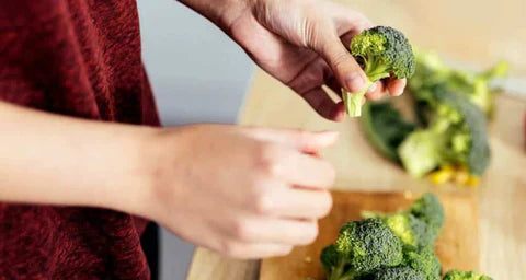 Person holding fresh broccoli to promote digestion with digestive enzyme supplements