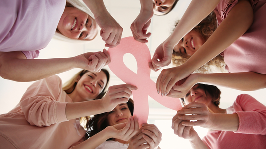 Group of diverse women holding a pink cancer awareness ribbon symbolizing courage and love