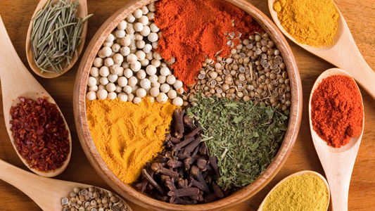Assorted colorful herbs and spices in wooden bowls and spoons for healthy digestion and gut health