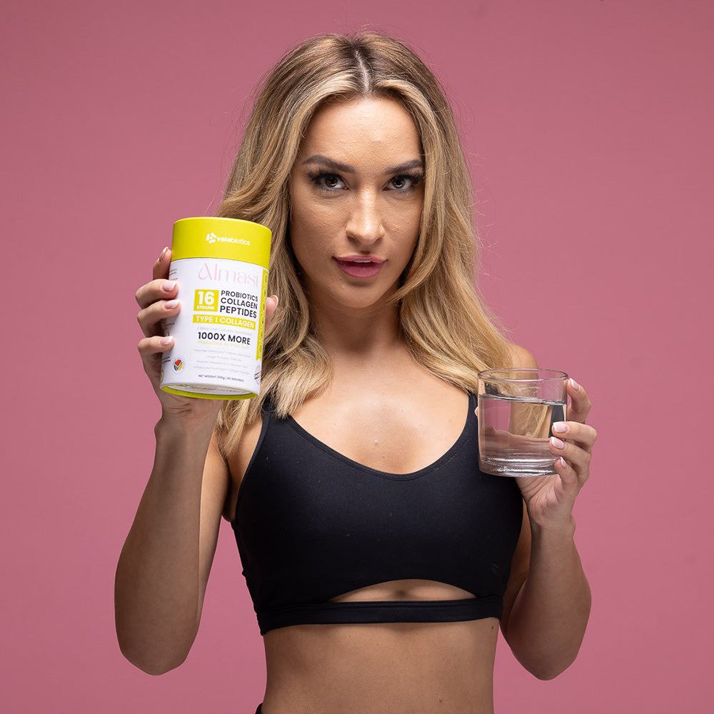 woman holding Almasi Probiotics Collagen Peptides powder container and glass of water for skin health