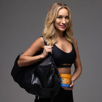 Fit woman holding GutSlim Probiotics Tummy Toner supplement container and gym bag for digestive health and belly fat reduction