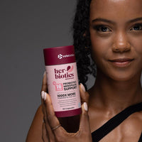 Her-Biotics Probiotics Menopausal Support supplement bottle held by woman promoting hormonal balance and gut health during menopause
