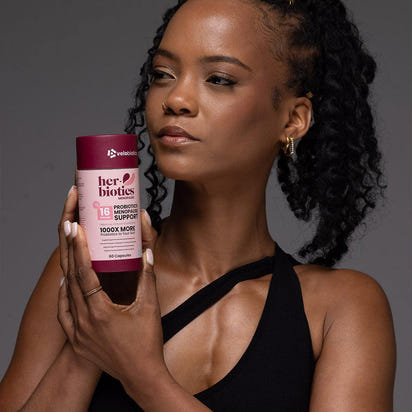 woman holding Her-Biotics Probiotics Menopausal Support supplement bottle for hormonal balance and vitality