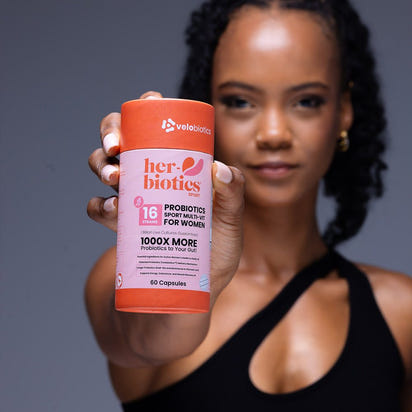 Woman holding Her-Biotics Sport Capsules probiotic multivitamin supplement for active women