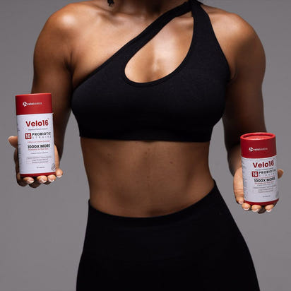 fit person holding two containers of Velo16 Probiotic Capsules for digestive health and immunity support