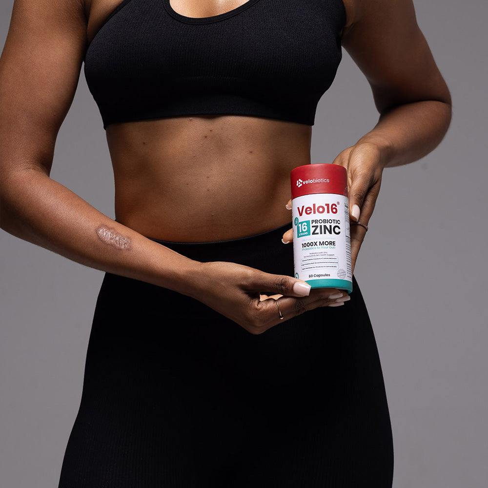 Person holding Velo16 Probiotics + Zinc Picolinate supplement container for gut and immune health support