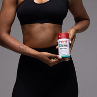 Person holding Velo16 Probiotics + Zinc Picolinate supplement container for gut and immune health support