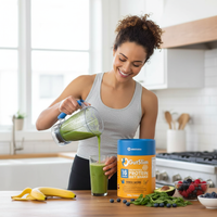Woman pouring green GutSlim Probiotics Diet Shake into glass in kitchen with fresh fruits and powder container nearby